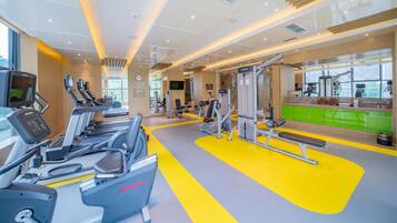 A modern gym with treadmills, weight machines, and a bright yellow floor.