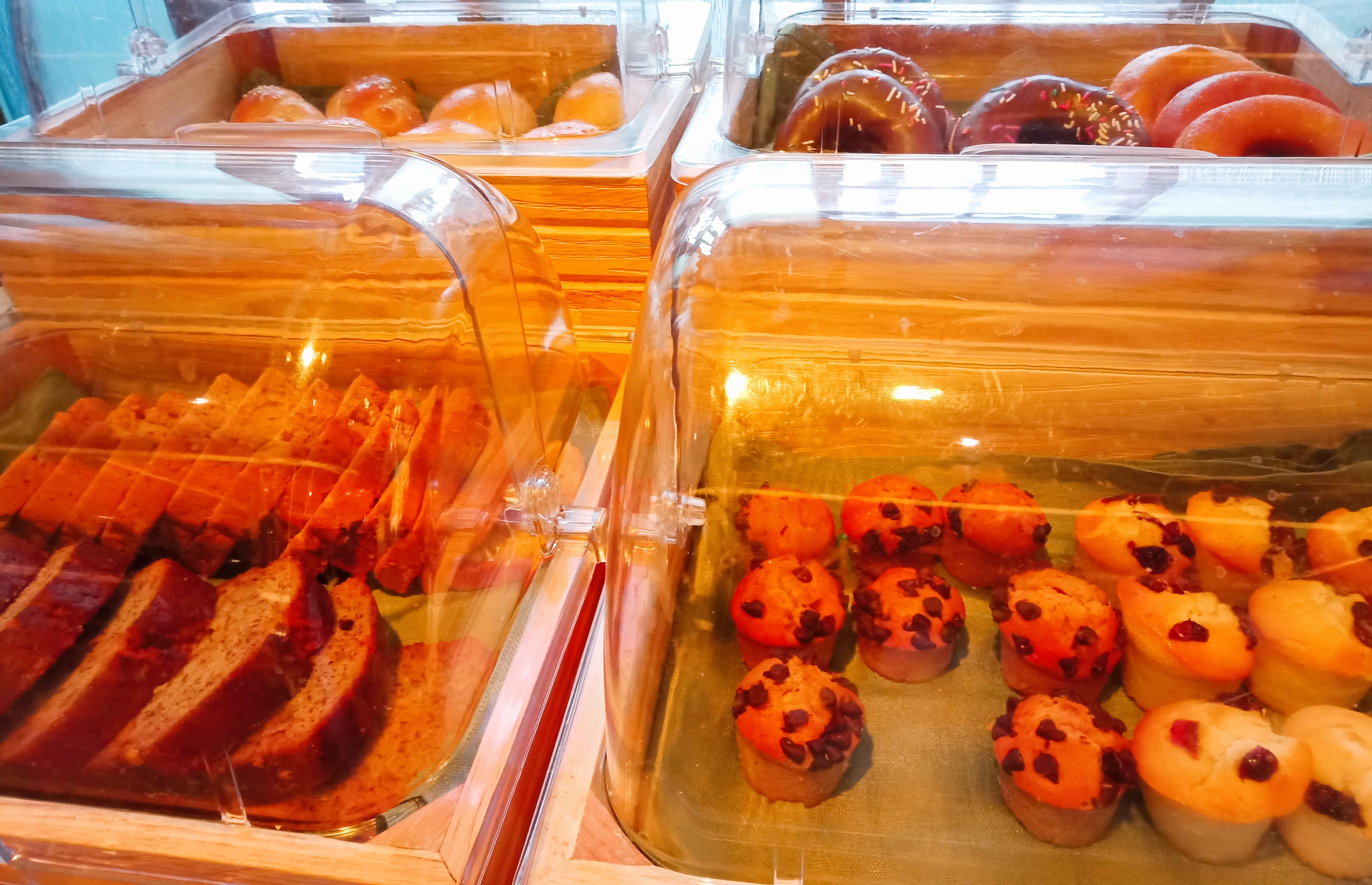 Una vitrina de panadería con distintos productos horneados en recipientes transparentes.