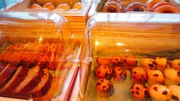 Una vitrina de panadería con distintos productos horneados en recipientes transparentes.