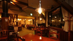 A restaurant with wooden furniture, hanging lights, and a sign reading "RESTAURANT". - Petit Resort Hotel Der Barte (Yamagata)