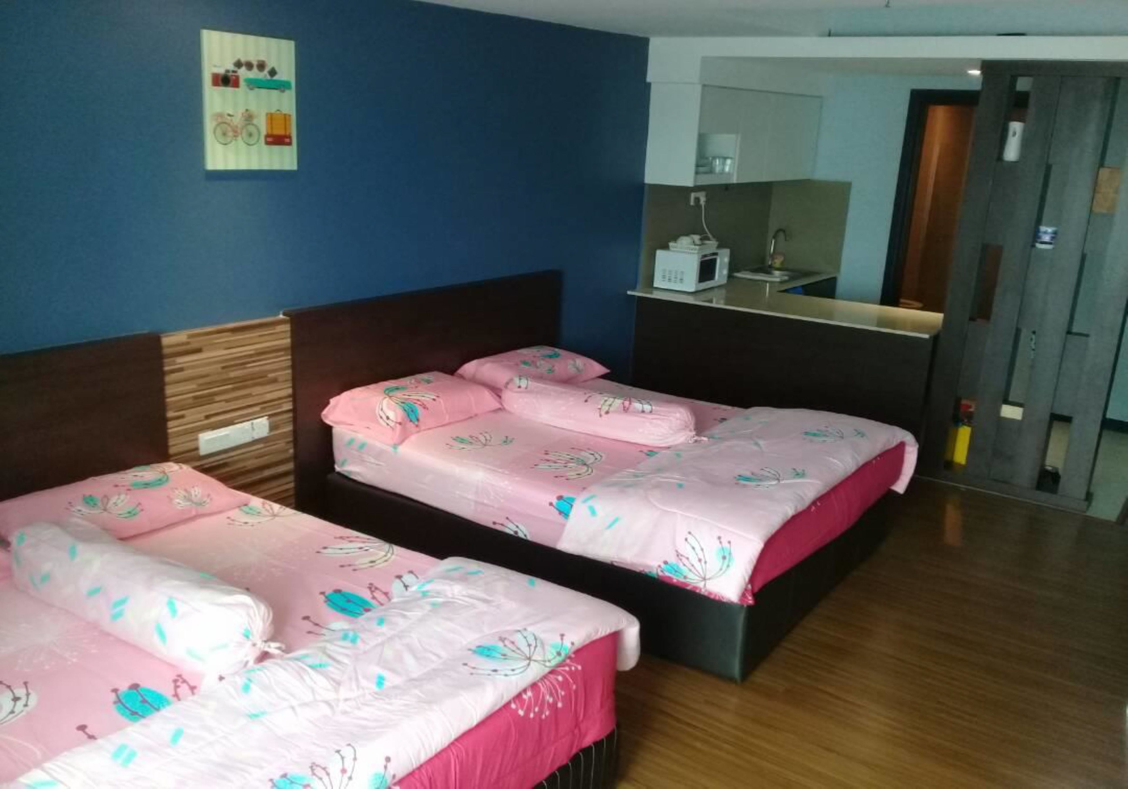 Una habitación de hotel con dos camas, cabecero de madera, una kitchenette pequeña y un espejo.