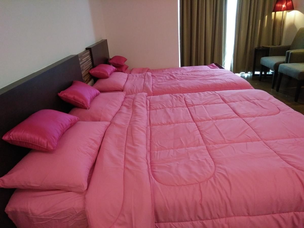 A hotel room with a large bed, multiple pillows, a headboard, and a lamp.