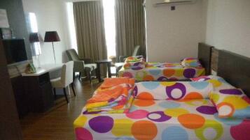 A hotel room with two beds, a desk, and a chair.