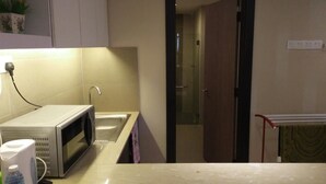 A compact kitchen with a microwave, sink, and a small countertop. - Best Studio Guest House (Kota Bharu)