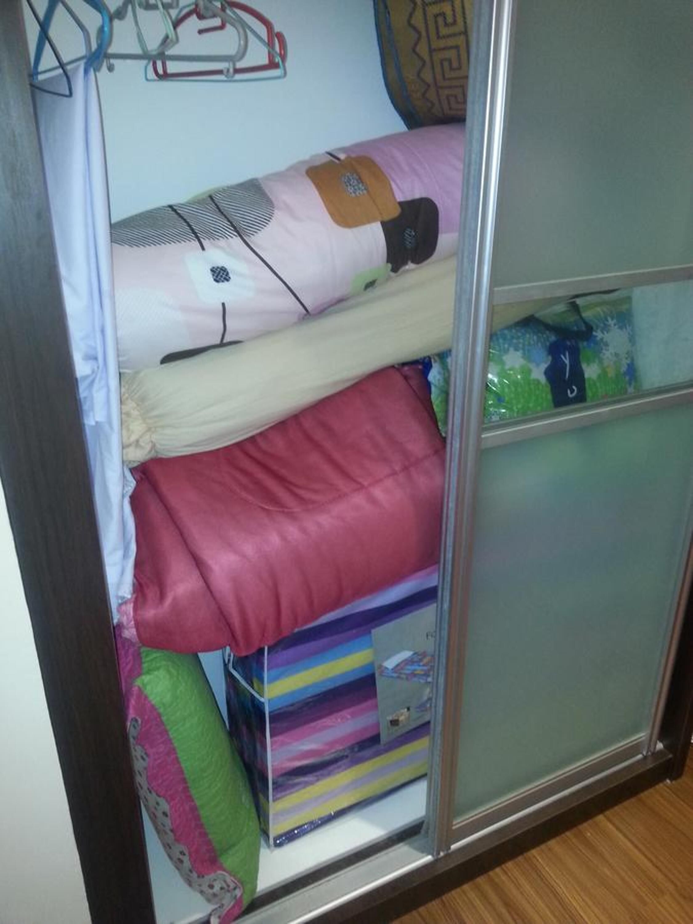 Una cama individual superpuesta con un compartimento inferior, que contiene una caja y almohadas.