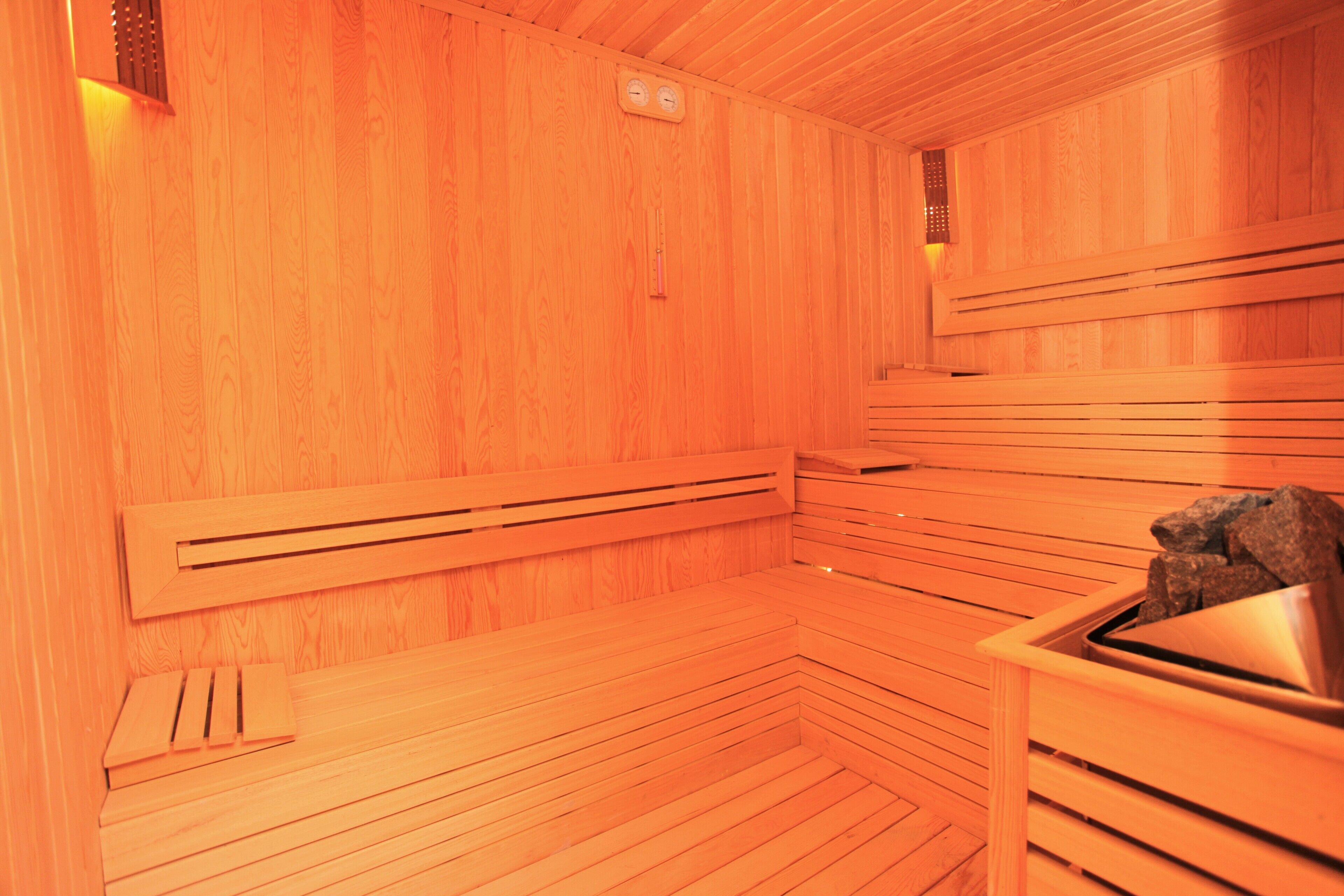 Eine Sauna mit Holzbänken und einem Metallbecken.