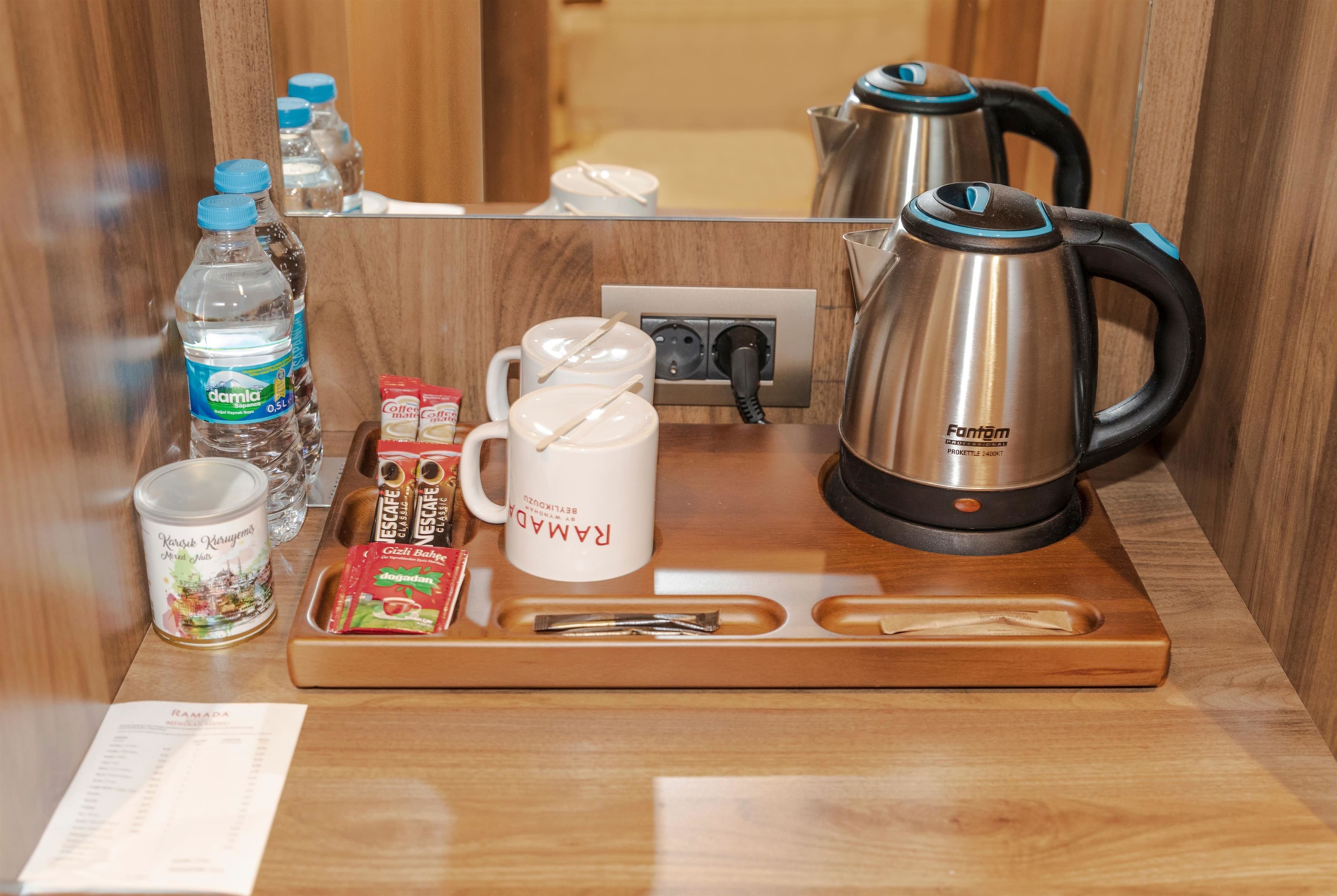 A wooden tray with a kettle, water bottles, coffee mugs, and a menu.