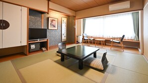 A traditional Japanese-style room with tatami flooring, a low table, and a television on a cabinet. - Mimatsukan (Shibukawa)