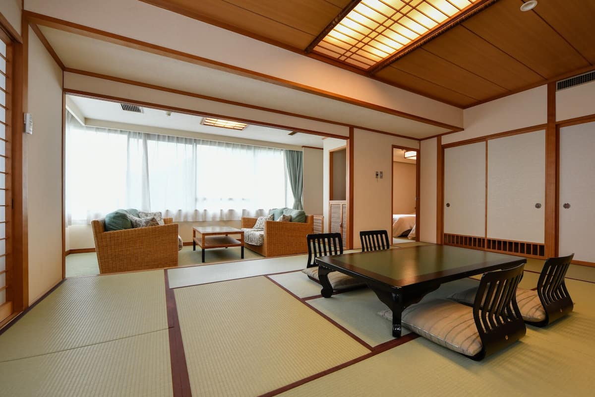 Una habitación japonesa tradicional con suelo de tatami, una mesa baja y puertas correderas shoji.