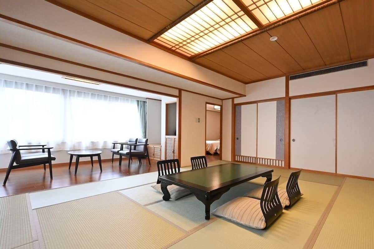 Una habitación japonesa tradicional con suelo de tatami, una mesa baja y puertas correderas.