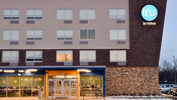 Een hotel met een modern design, met een combinatie van bakstenen en glazen gevels, grote ramen en een opvallend logo.