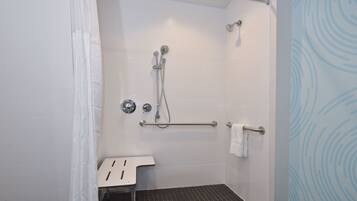 A shower area with a grab bar, a white sink, and a towel rack.