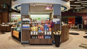Een kiosk met verschillende snacks en drankjes, een koffieapparaat, en een bordje voor een winkel met lokale producten.