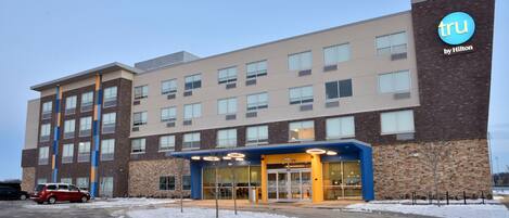 A modern hotel with a brick facade, multiple windows, and a blue entrance.