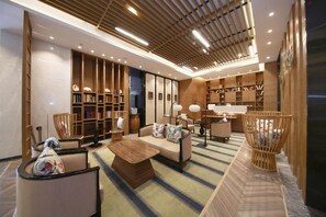 Een modern interieur met een bank, fauteuils, een salontafel en boekenkasten.