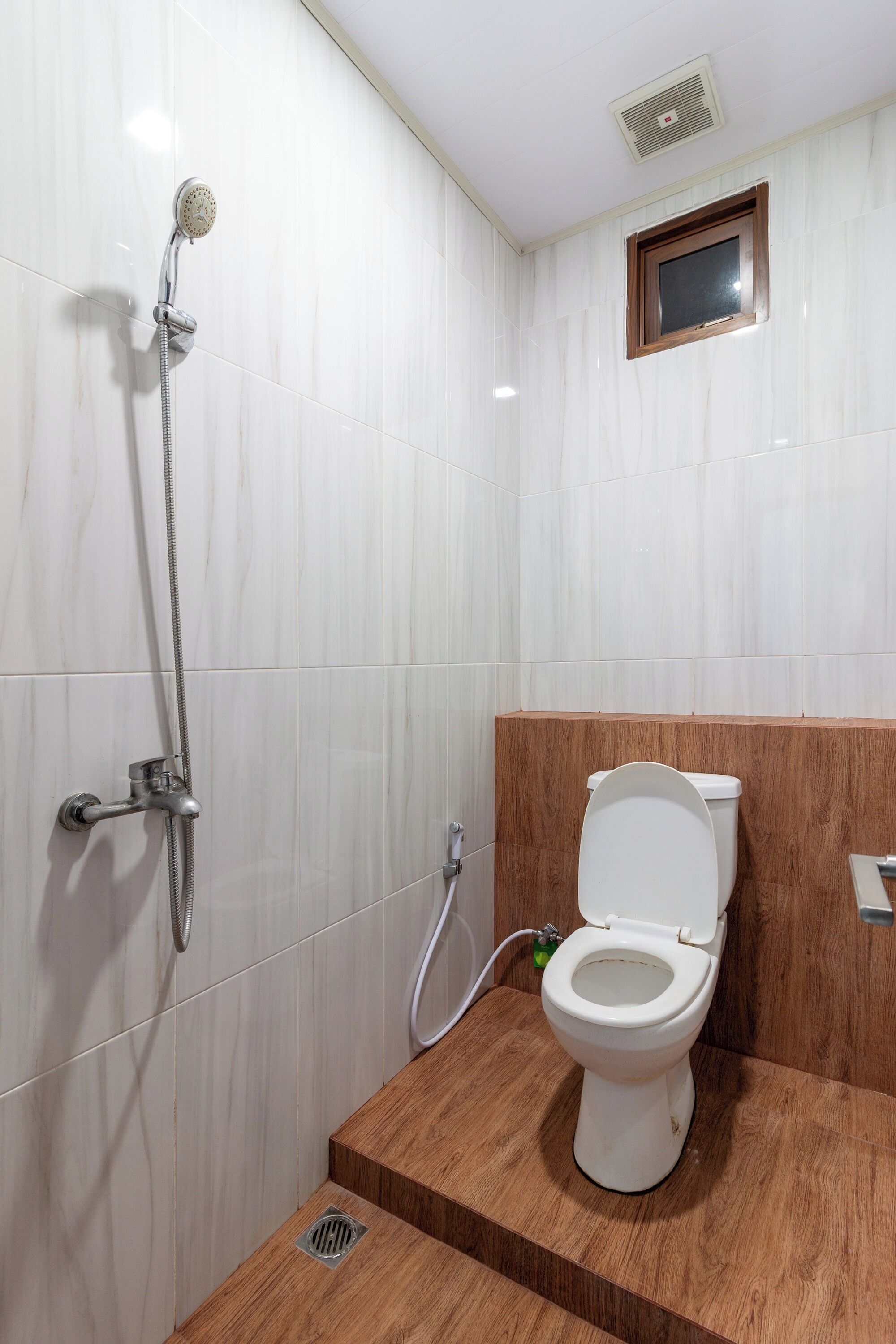 Une salle de bain avec une douche, des toilettes et une petite fenêtre.