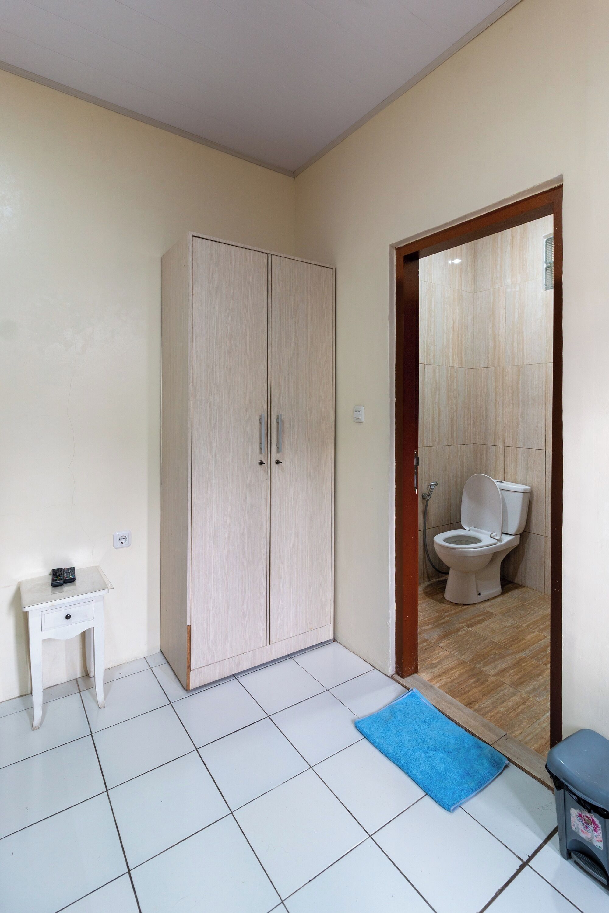 A room with a wardrobe, a small table, and a blue mat on the floor.