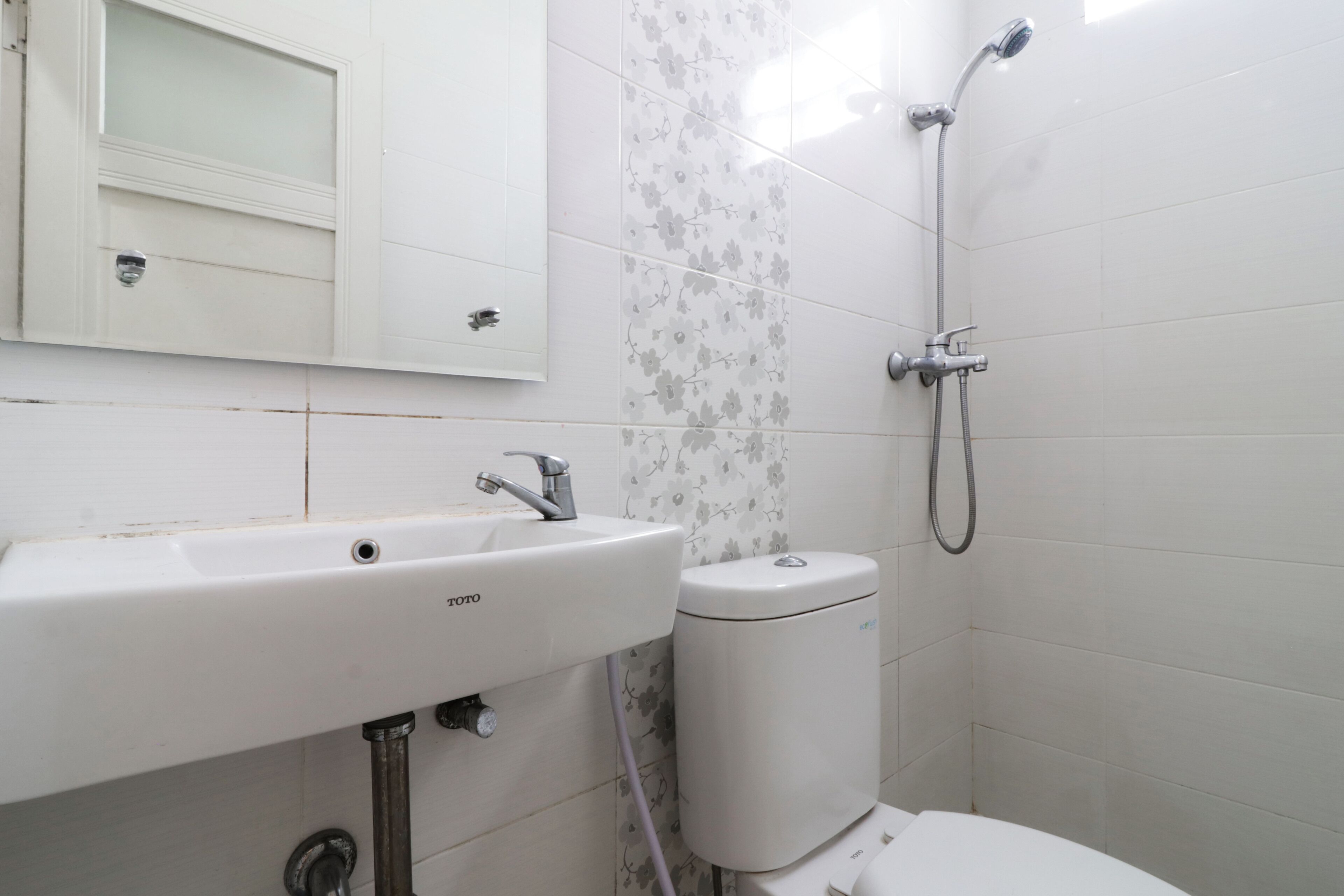 Une salle de bain avec un lavabo, des toilettes et une douche, le tout de couleur blanche.