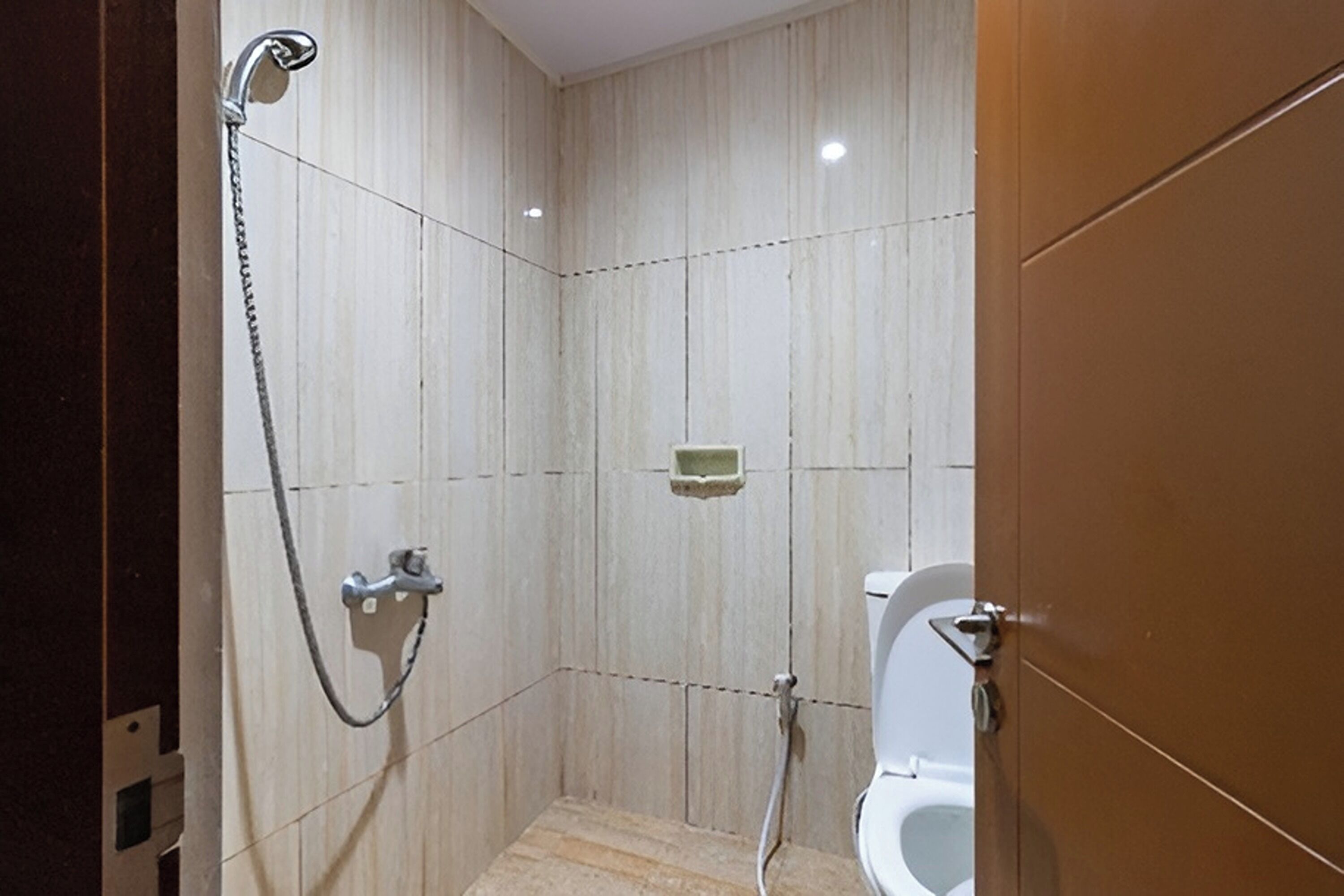 Un baño pequeño con azulejos, que incluye una ducha, inodoro y un jabonera en la pared.