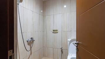 Un baño pequeño con azulejos, que incluye una ducha, inodoro y un jabonera en la pared.