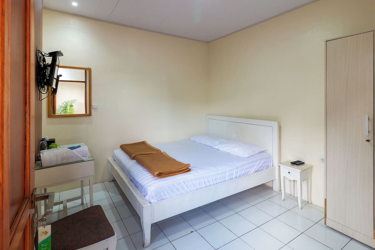 A bedroom with a bed, a bedside table, a wardrobe, and a mirror.