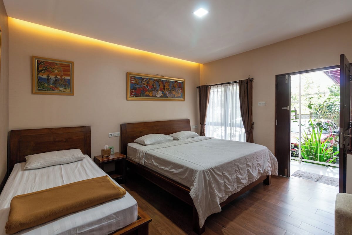 A bedroom with two beds, a wooden headboard, a nightstand, and a painting on the wall.