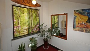 Una habitació amb una finestra gran, un mirall i un quadre a la paret.