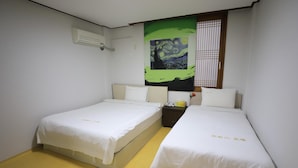 Una habitació amb dos llits, aire condicionat fixat a la paret i un quadre gran a sobre dels llits.