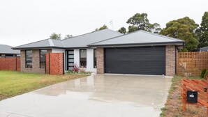 A modern two-story house with a garage, a driveway, and a fenced yard. - Euphoria House (Wynyard)