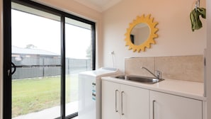 A kitchen with a built-in dishwasher, a sink, and a large window. - Euphoria House (Wynyard)