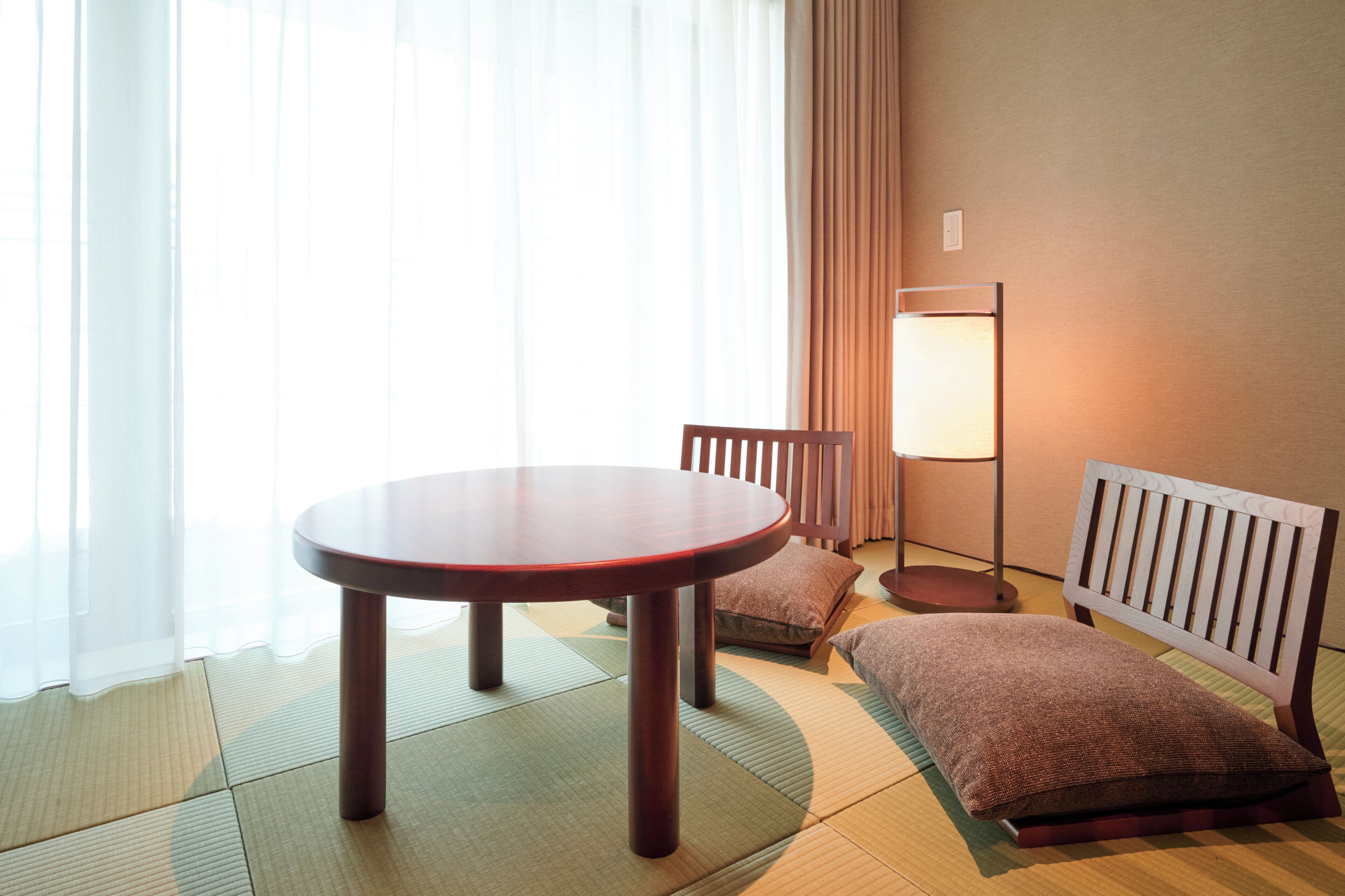A room with tatami flooring, a wooden table, a chair, a floor lamp, and a radiator.