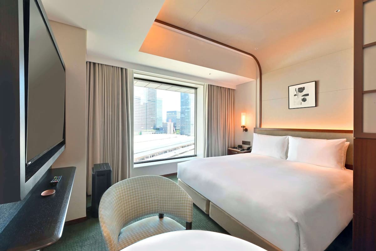 A hotel room with a large bed, a television, a desk, and a chair.