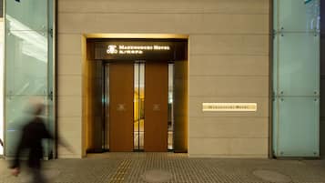The Marunouchi Hotel entrance with a modern design, featuring a signboard and a nameplate on the wall.