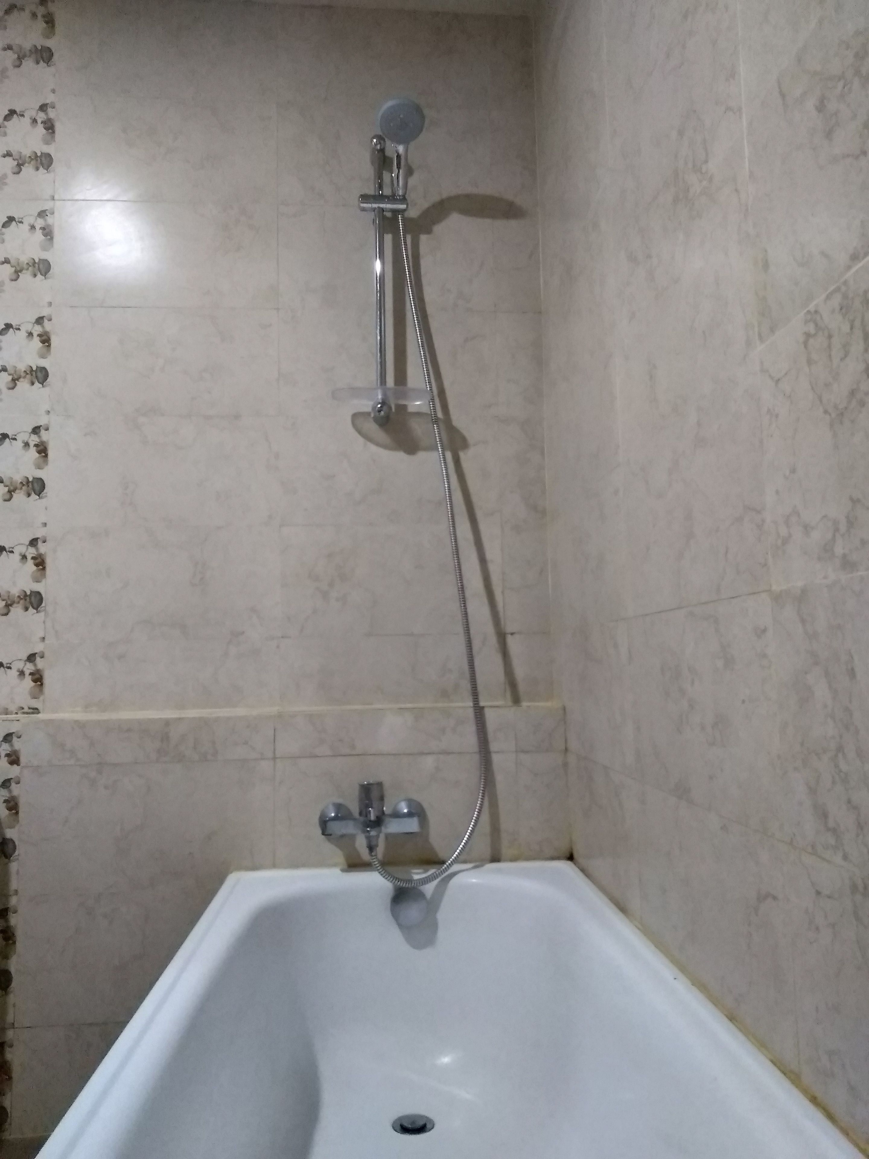 Un baño con bañera, cabezal de ducha y grifo.