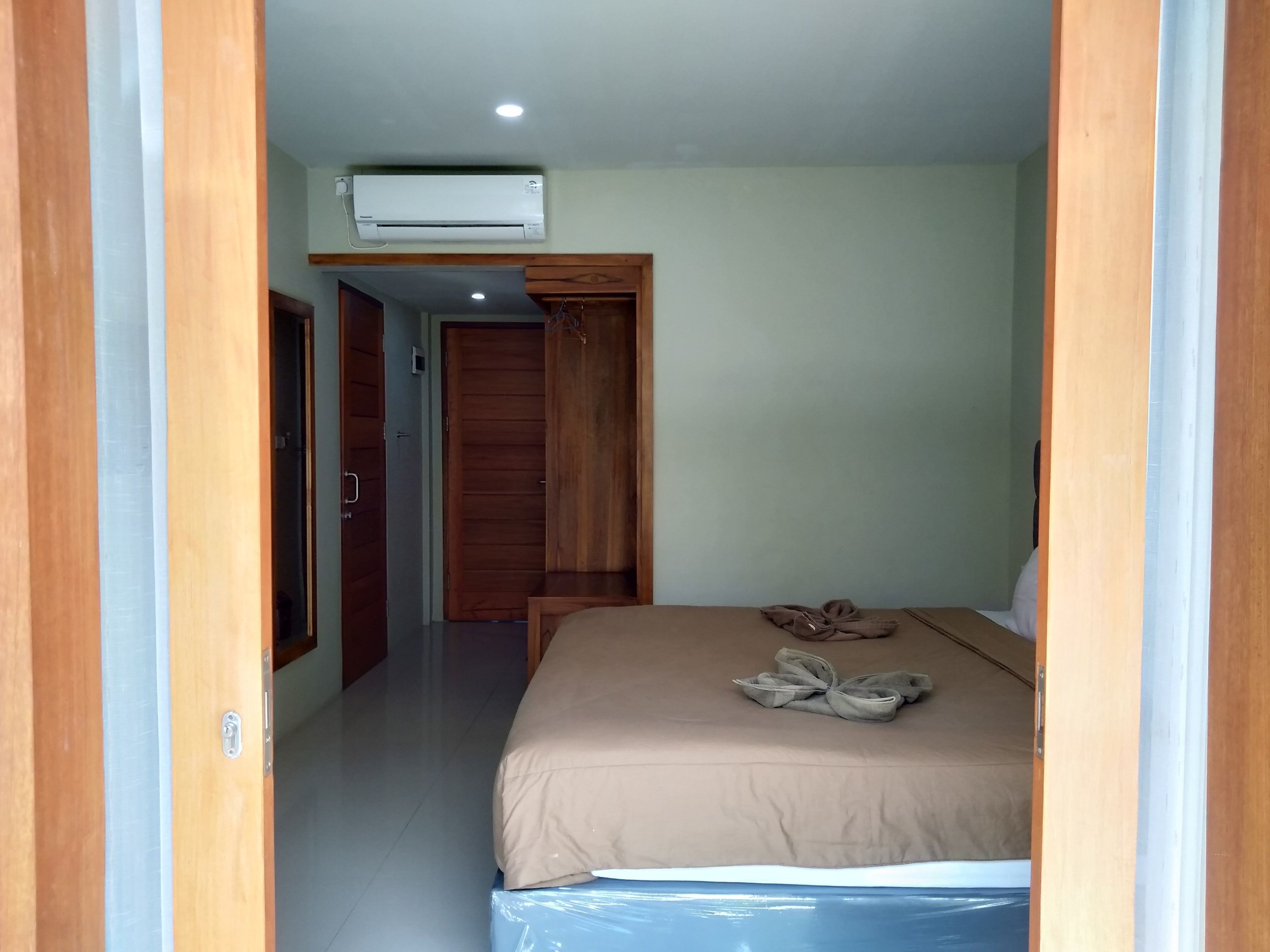 A bedroom with a bed, a wooden wardrobe, and an air conditioning unit.
