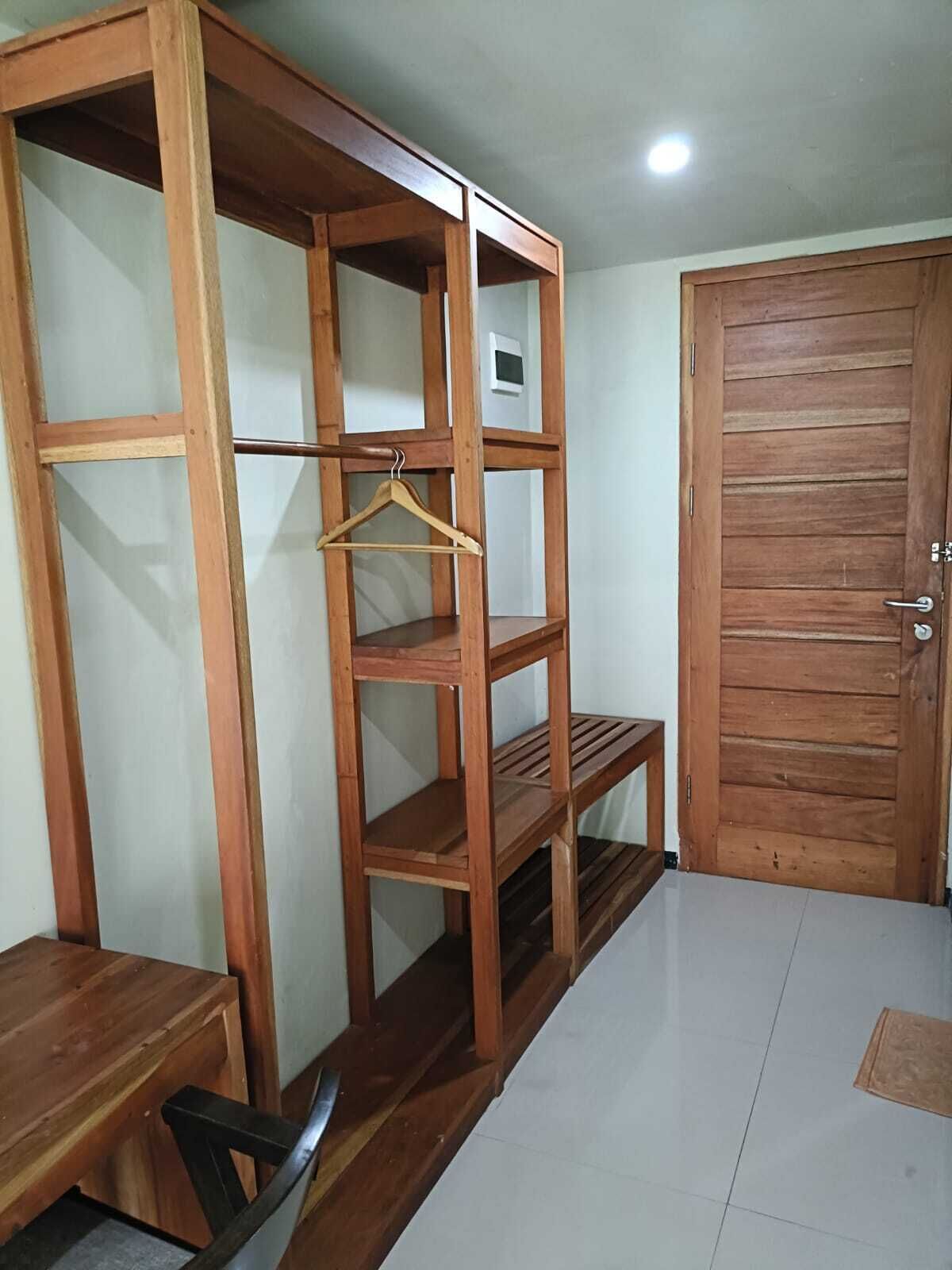 Une pièce avec une armoire en bois, un banc en bois et une porte.