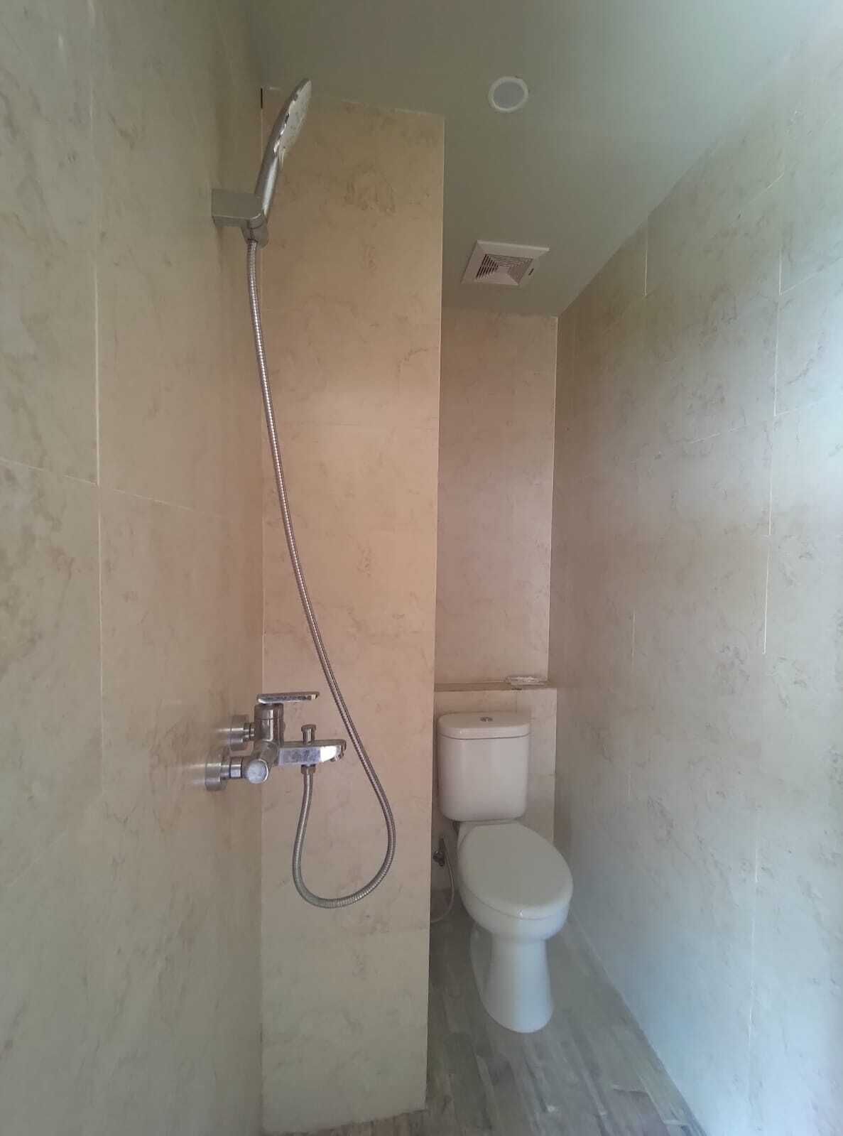 Een badkamer met een douche, toilet en een geïntegreerde ventilatiefan.