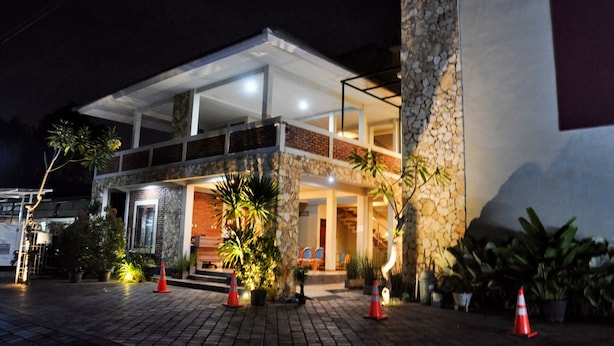 A hotel with a stone facade, a covered entrance, and outdoor seating.