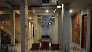A hallway with a staircase on the left, a brick wall on the right, and a sign indicating room numbers 105-110.