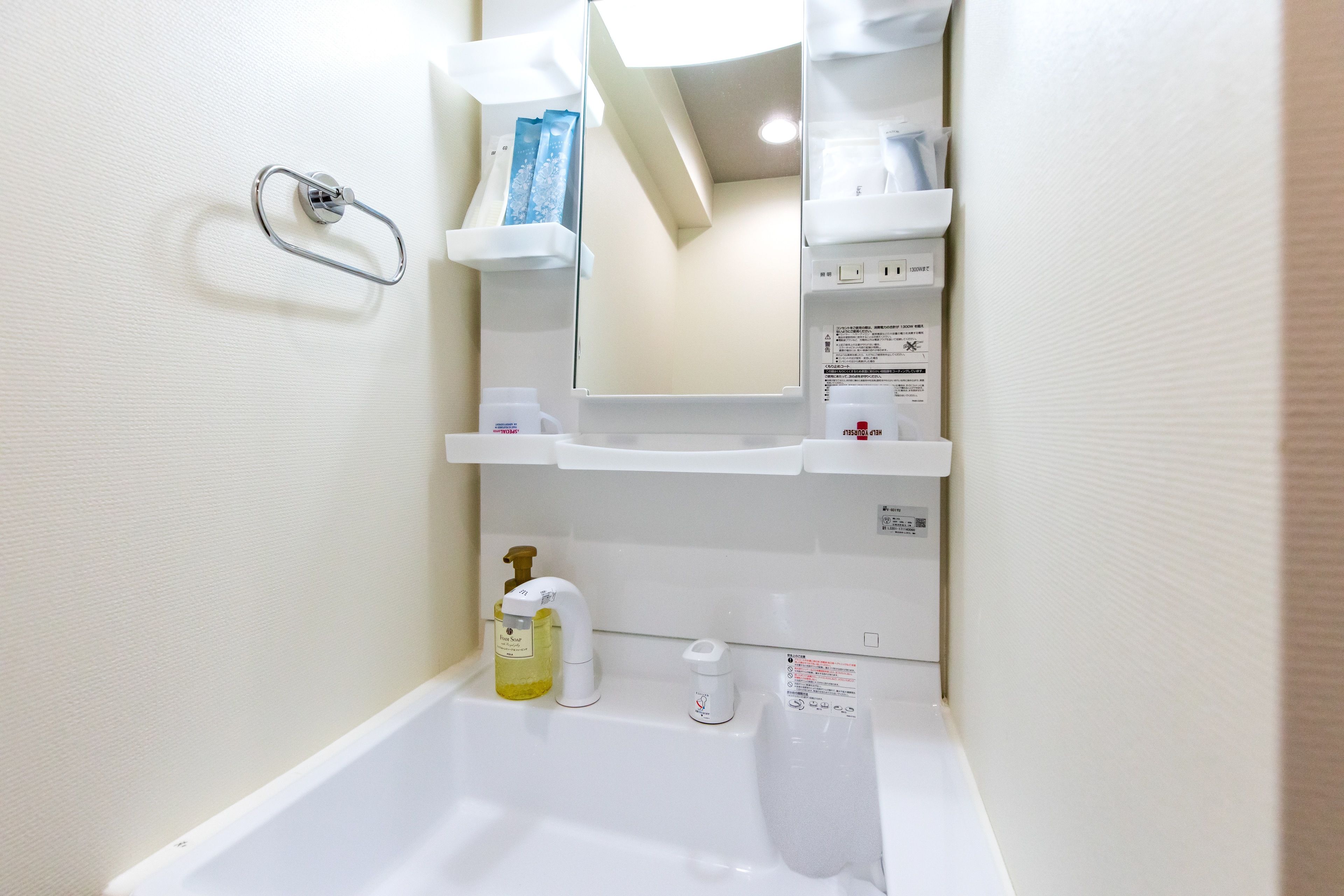 A bathroom with a bathtub, a hand soap dispenser, a paper towel dispenser, and a mirror.