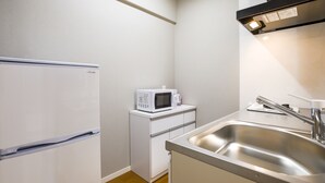 A compact kitchen with a refrigerator, microwave, and stainless steel sink. - Mr.KINJO in Arcade (Naha)