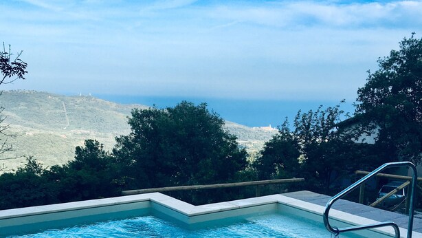 Une piscine offrant une vue sur un paysage vallonné et un ciel dégagé.