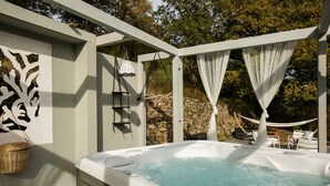Un bain à remous avec un mur en pierre en arrière-plan, un hamac et des paniers en osier.