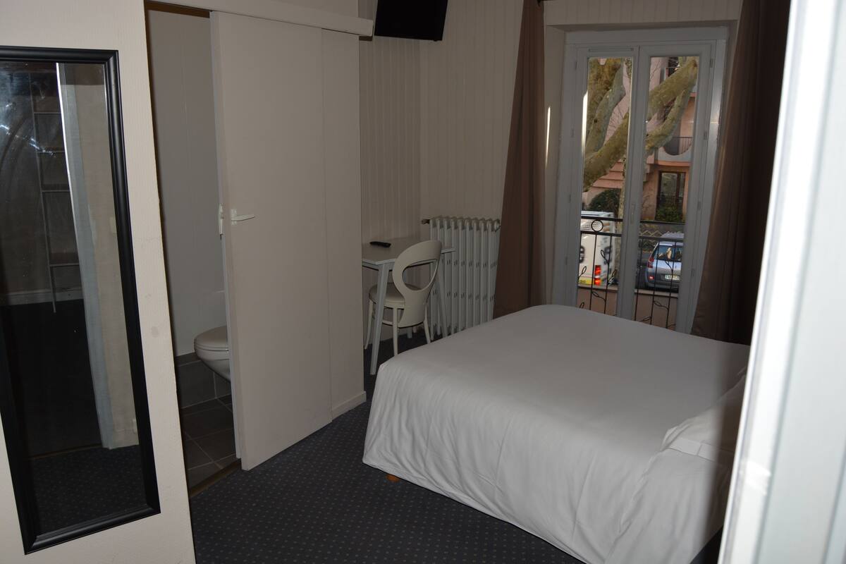 A hotel room with a bed, a desk, and a chair.