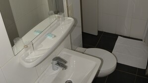Un baño con lavamanos, espejo y retrete.