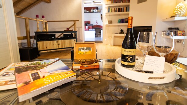 Una mesa con una botella de vino, copas, un sacacorchos, un atril para sacacorchos y una tarjeta de bienvenida.