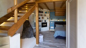 Un dormitorio con una escalera de madera, una estantería, una cama y un pequeño armario blanco.