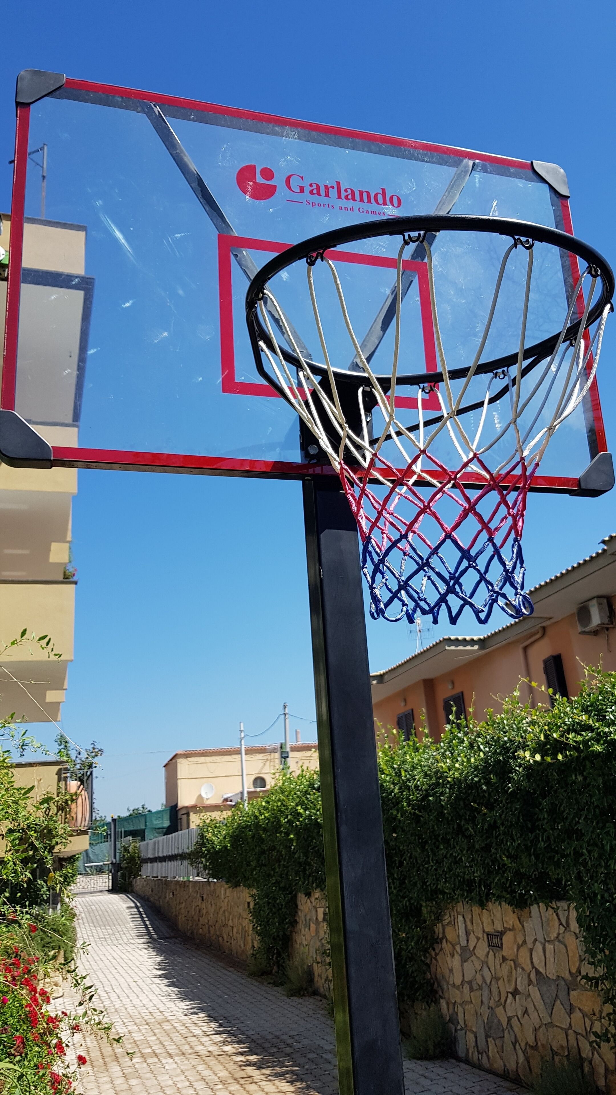 A basketball hoop with a red and blue frame, labeled "Garlando Sports and Games."