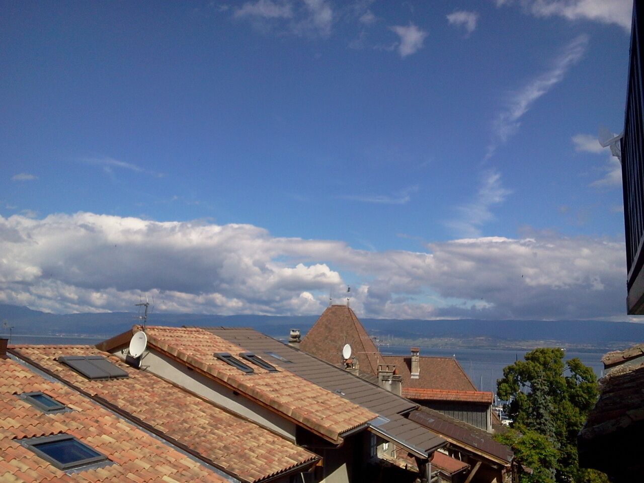 Una azotea con múltiples antenas parabólicas, vistas despejadas del mar y un paisaje urbano distante.