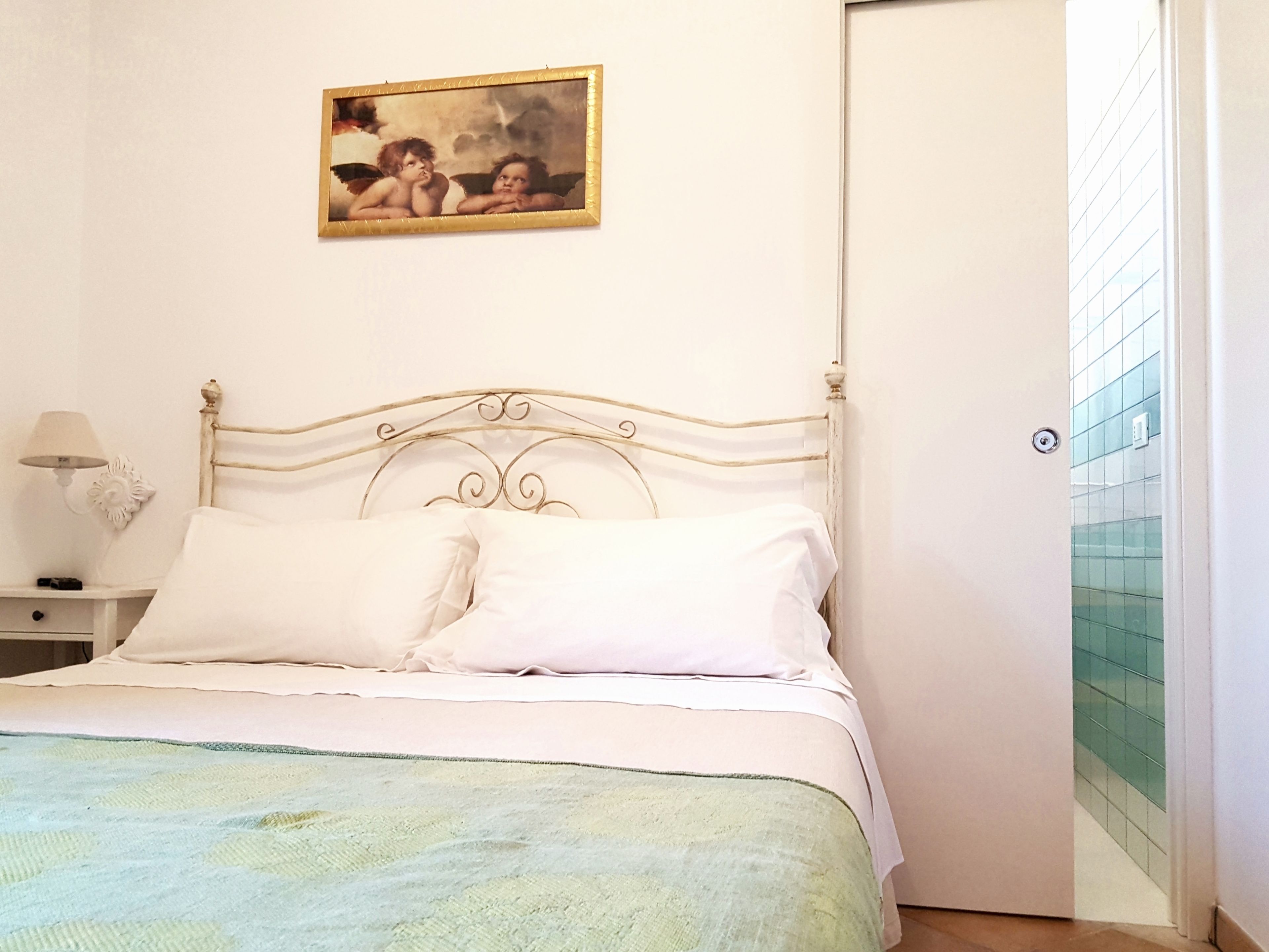 Una camera da letto con un letto, un comodino, una lampada e un quadro appeso al muro.